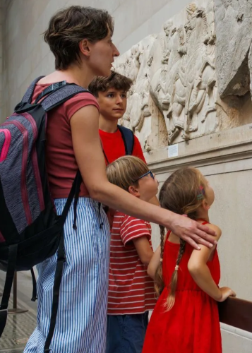 Két farmernadrágos gyermek áll egy téglafal előtt, közöttük egy szürke hátizsák hever a földön. Iskolakezdés, barátság, gyerekek, iskolatáska, hátizsák, tanévkezdés, hétköznapi pillanat.